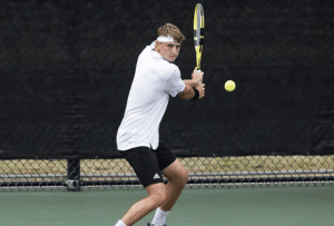 Texas A&M men's tennis player making a backhand shot during practice.